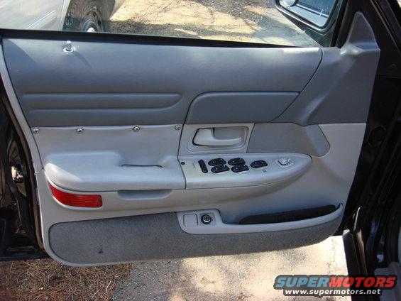 Interior door panel of a 2003 Ford Crown Victoria, showing power window controls and gray trim