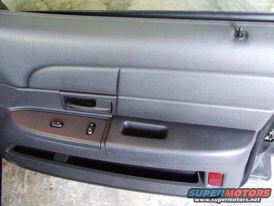 Gray car door panel with power window switches and a red reflector