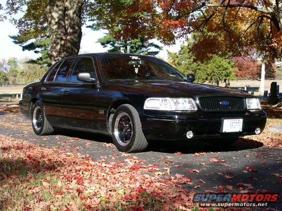 Black 2001 Ford Crown Victoria parked on a paved surface with fallen leaves