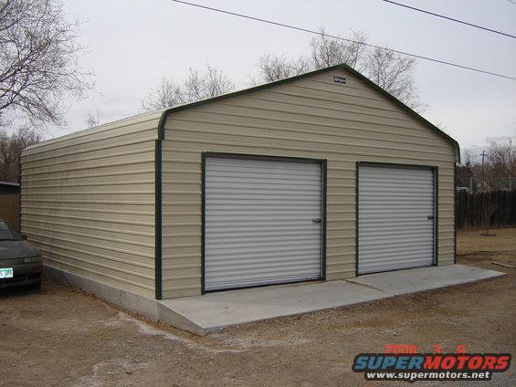 Metal garage with two roll-up doors and a dark-colored car parked on the left