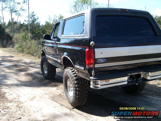 Black 1992 Ford Bronco on a dirt road, lifted with large tires