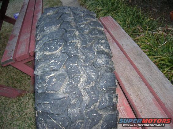 Mud-caked off-road tire resting on red wooden planks