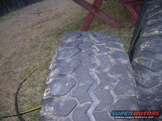 Two off-road tires with aggressive tread patterns are shown in close-up, one partially obscuring the other