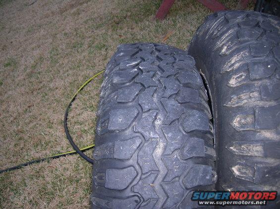 Two off-road tires with aggressive tread patterns are placed side-by-side on grass