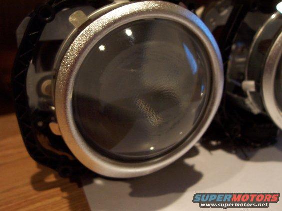 Close-up of a car headlight projector assembly with a silver bezel