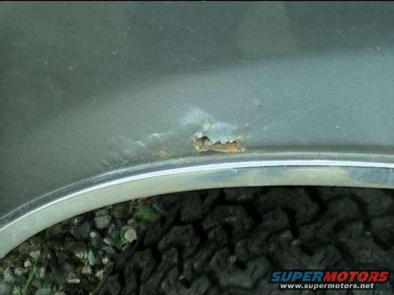 Rust hole on fender flare above tire