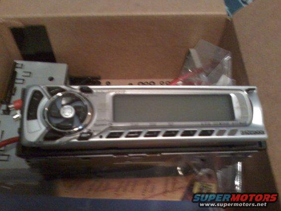 Silver car stereo with a digital display and a circular fan on the left