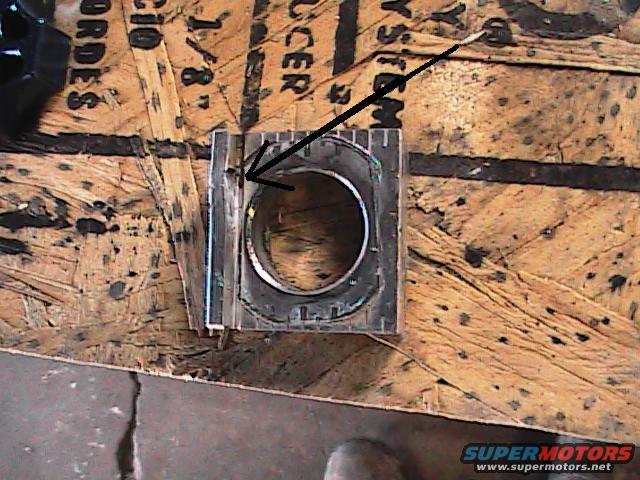 Close-up of a motorcycle engine part with an arrow pointing to a bolt