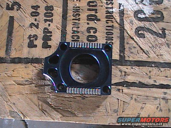 Black motorcycle part with circular opening, on wood with text
