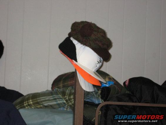 Several hats and winter clothing piled on a rack