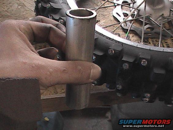 Hand holding metal tube near motorcycle tire and spokes