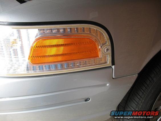 Silver 2004 Ford Crown Victoria front corner with clear turn signal and orange reflector