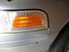 2004 Ford Crown Victoria - Close-up of the front corner of a silver 2004 Ford Crown Victoria, highlighting the clear turn signal and orange reflector assembly.
