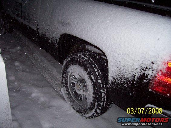2008 Chevrolet Silverado 1500 rear tire covered in snow, with tire tracks visible