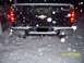 2008 Chevrolet Silverado 1500 - Rear view of a black Chevrolet Silverado pickup truck during a snowfall, showing its dual exhaust and gold bowtie emblem.