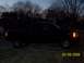2008 Chevrolet Silverado 1500 - A black 2008 Chevrolet Silverado 1500 is parked in a grassy area at dusk, with trees and houses in the background.