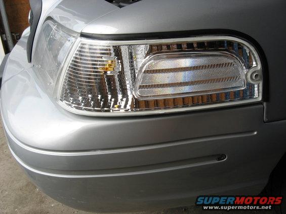 Silver car front corner with clear turn signal and ribbed headlight