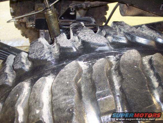 Close-up of large tire tread and suspension components