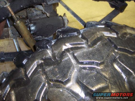Close-up of a knobby off-road tire tread and part of the suspension system
