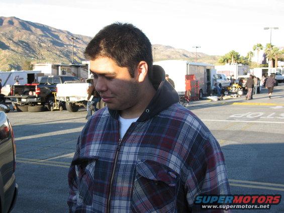 Man in plaid jacket with vehicles and trailers in background
