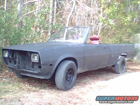 Custom convertible pickup truck with red seats, matte black paint, and no grille