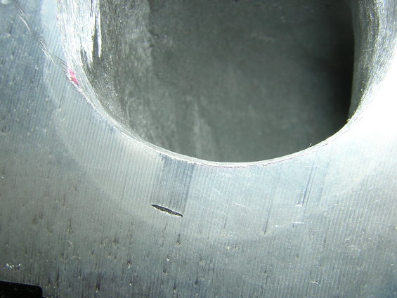Close-up of an engine intake port with machining marks and a small crack