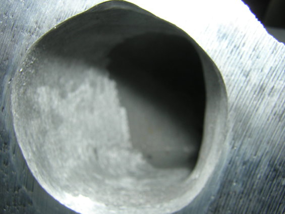 Close-up of a rough, metallic engine intake port with visible machining marks