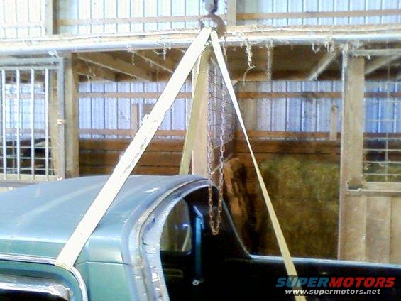 Green SUV roof and interior being lifted by straps and chains in a barn