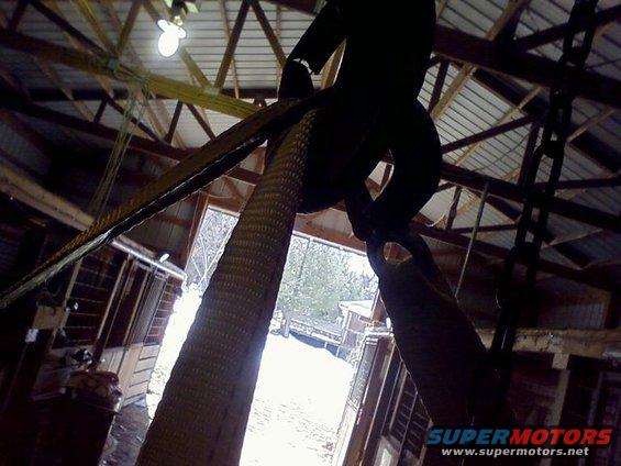 Overhead hoist and straps inside a barn, looking out a large open doorway