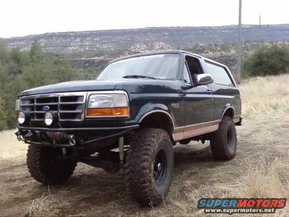 Dark green 1995 Ford Bronco with lifted suspension and off-road tires parked on a dirt hill