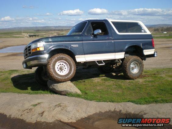 1993 Ford Bronco, 3q-front view, dark blue with white top, lifted suspension, off-road tires