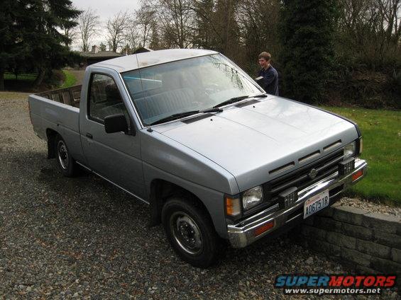 Silver pickup truck parked on gravel, front quarter view