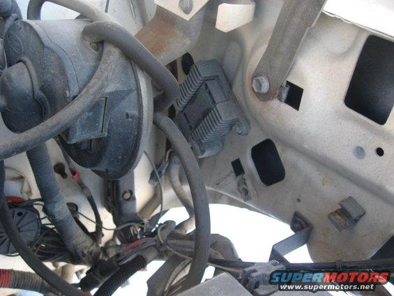 Engine bay wiring and components, including a black plastic housing and metal brackets