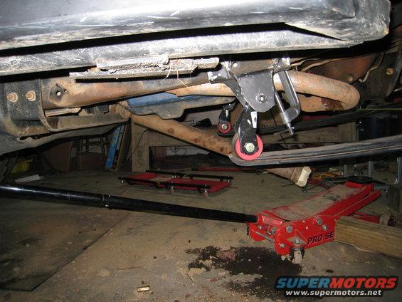 Undercarriage of a vehicle with leaf springs and a red floor jack