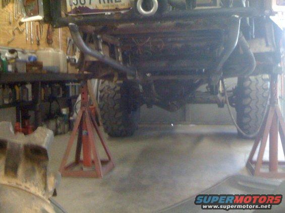 Undercarriage of a vehicle on jack stands, showing suspension and tires