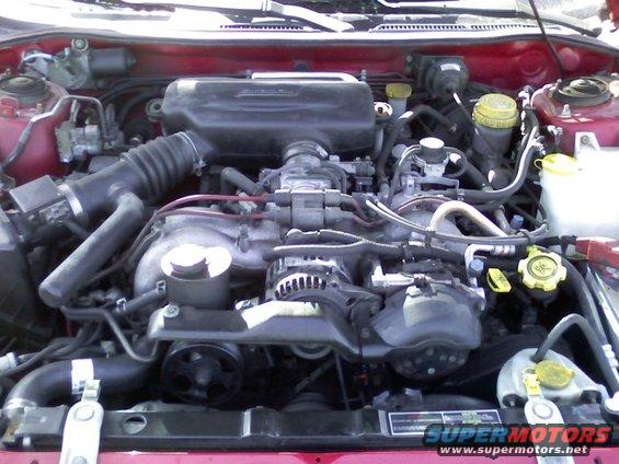 Red engine bay with a Subaru engine, hoses, and belts visible. A 'SUPERMOTORS' watermark is present