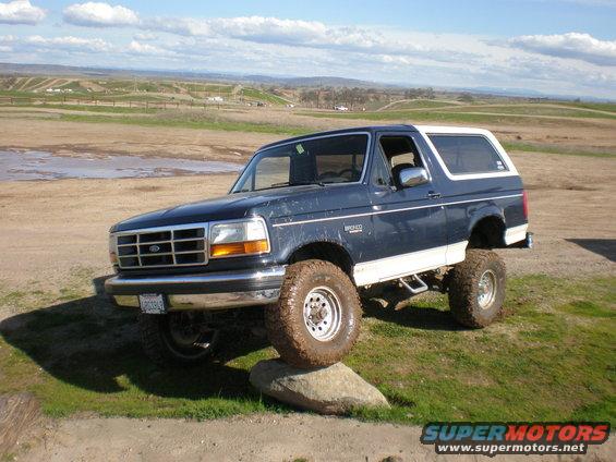 Dark blue and white lifted Ford Bronco with off-road tires on a rock