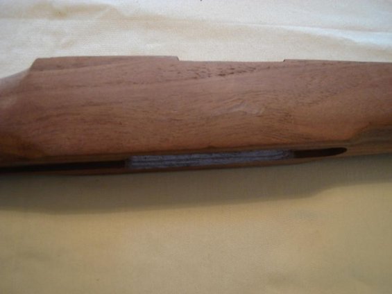 Wooden gun stock with a recessed area showing layered material