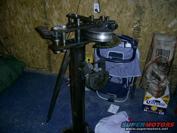Tube bender with metal rollers and adjustable dies, set on a stand