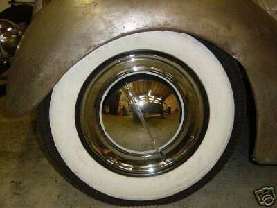 1936 Ford Coupe wheel with whitewall tire and chrome hubcap, showing reflection of interior