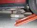 2004 Ford Crown Victoria - A red car's undercarriage is shown with an oil drain pan positioned to catch fluid.