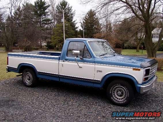 Blue and white Ford F-150 pickup truck parked on gravel