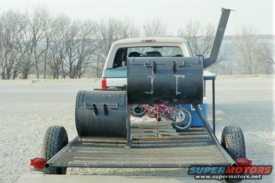 Trailer loaded with a large smoker and a child's bicycle, towed by an SUV