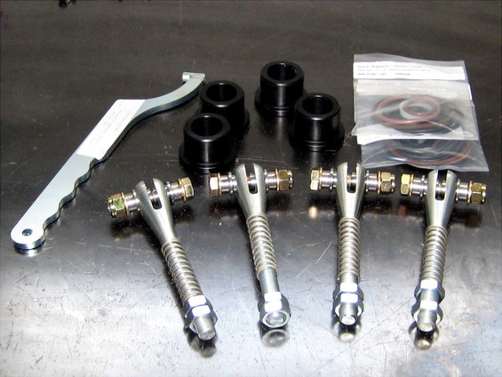 Set of four adjustable control arms, black bushings, and a specialized wrench laid out on a metal surface