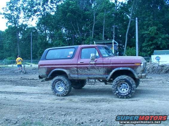 Mud-covered maroon Ford Bronco, side view, lifted suspension, off-road tires
