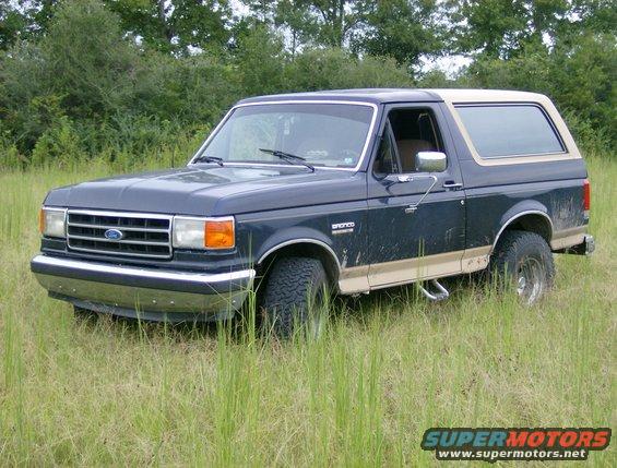 Dark blue Ford Bronco with tan trim parked in tall grass