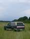 1990 Ford Bronco - A 1990 Ford Bronco sits in a grassy field under a cloudy sky.