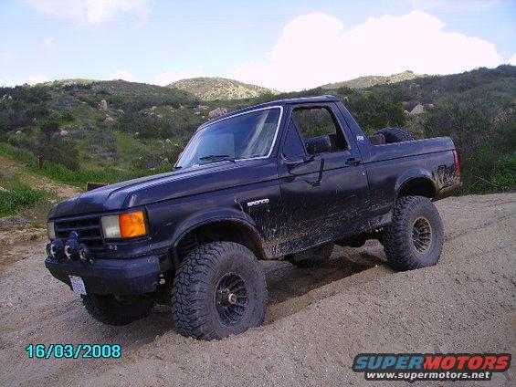 Black Ford Bronco on a dirt hill, lifted with large tires