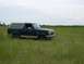 1990 Ford Bronco - A dark blue and tan Ford Bronco sits in a grassy field under a cloudy sky.