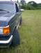 1990 Ford Bronco - A dark blue Ford Bronco is parked in a grassy field, viewed from the front quarter panel.
